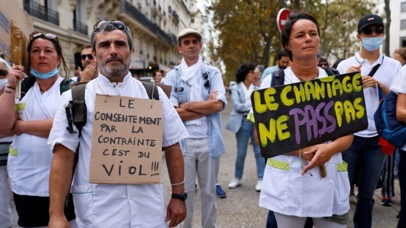 Un hombre sostiene un cartel en el que se lee "El consentimiento por la fuerza es una violación" durante una protesta contra la vacunación obligatoria contra covid-19 para ciertos trabajadores, y el uso obligatorio del certificado sanitario para acceder a la mayoría de los espacios públicos, frente al Ministerio de Salud en París (Francia) el 11 de septiembre de 2021. (Thomas Samson/AFP vía Getty Images)