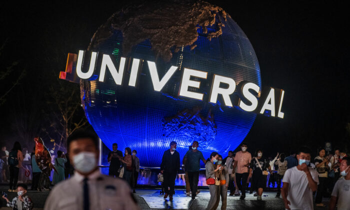 Varias personas caminan por el parque temático de Universal Studios Beijing delante del globo terráqueo de la marca el 23 de septiembre de 2021. (Kevin Frayer/Getty Images)