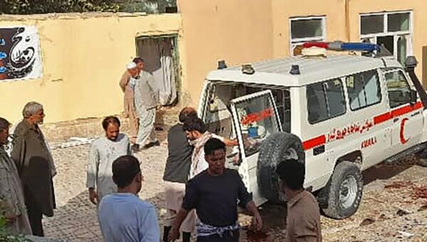 Unos hombres afganos permanecen junto a una ambulancia tras un atentado en una mezquita de Kunduz el 8 de octubre de 2021. (AFP vía Getty Images)