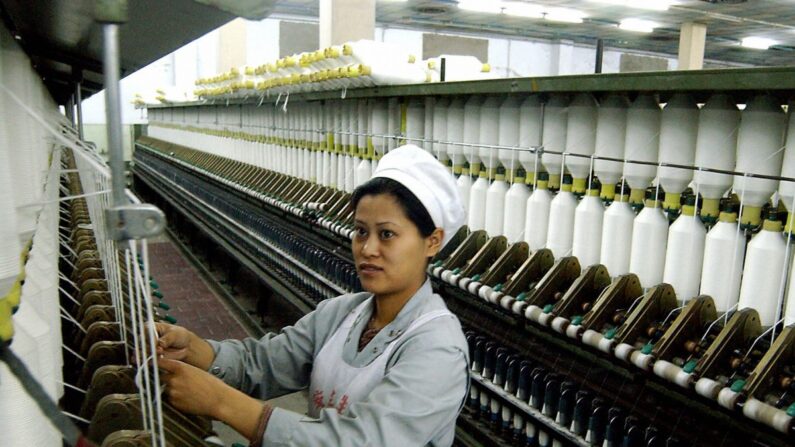 Una trabajadora china realiza sus tareas en una fábrica de textiles para la exportación en Haikou, en la isla meridional china de Hainan, el 30 de marzo de 2004. Los datos actuales y las anécdotas indican que los fabricantes extranjeros buscan lugares de producción más baratos que China. (AFP/Getty Images) 