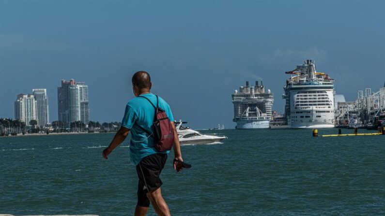 Fotografía del 1 de marzo de 2021 donde aparece un hombre mientras camina frente a dos cruceros de diferentes compañías atracados en la Bahía de Miami, Florida. EFE/Giorgio Viera