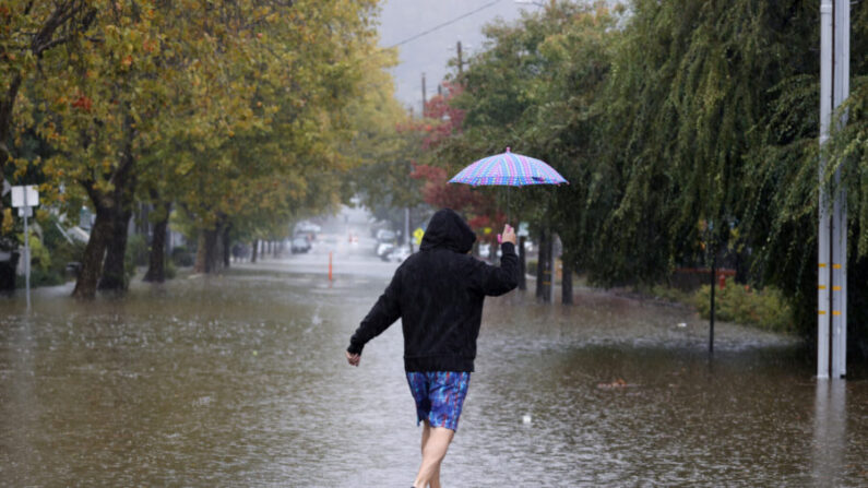 Un peatón lleva un paraguas mientras camina por una calle inundada en San Rafael, California, el 24 de octubre de 2021. (Justin Sullivan/Getty Images) 
