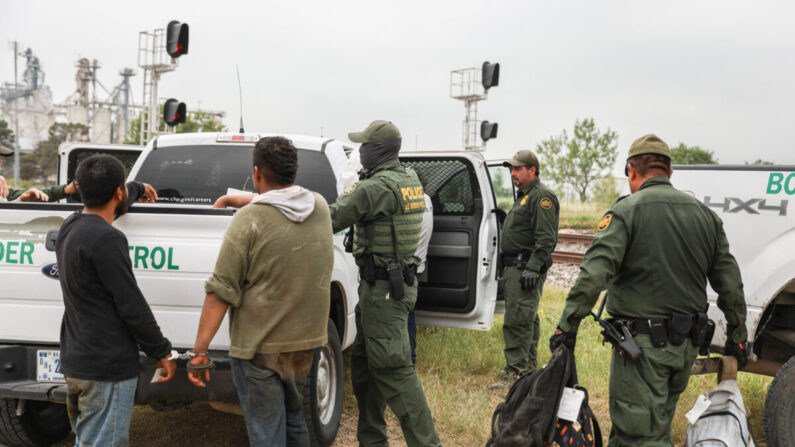 Agentes de la Patrulla Fronteriza detienen a extranjeros ilegales de México que se habían escondido en una tolva de granos en un tren de carga que se dirigía a San Antonio, cerca de Uvalde, Texas, el 21 de junio de 2021. (Charlotte Cuthbertson/The Epoch Times)