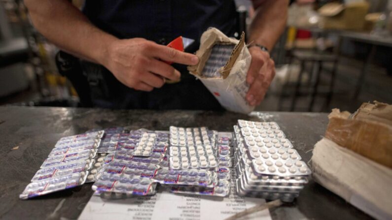Un agente de la División de Comercio y Carga de la Oficina de Aduanas y Protección de Fronteras de Estados Unidos encuentra pastillas de oxicodona en un paquete en las instalaciones del Servicio Postal de Estados Unidos en el aeropuerto John F. Kennedy, en Nueva York, el 24 de junio de 2019. (Johannes Eisele/AFP vía Getty Images)