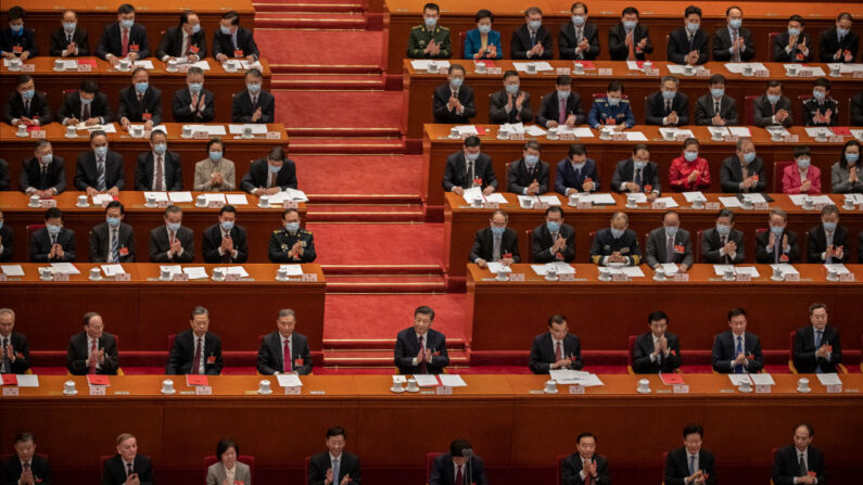 El líder de China, Xi Jinping, en el centro, y los legisladores aplauden tras votar a favor de una resolución para revisar el sistema electoral de Hong Kong, durante la sesión de clausura de la Asamblea Popular Nacional en el Gran Salón del Pueblo el 11 de marzo de 2021 en Beijing, China. (Kevin Frayer/Getty Images)