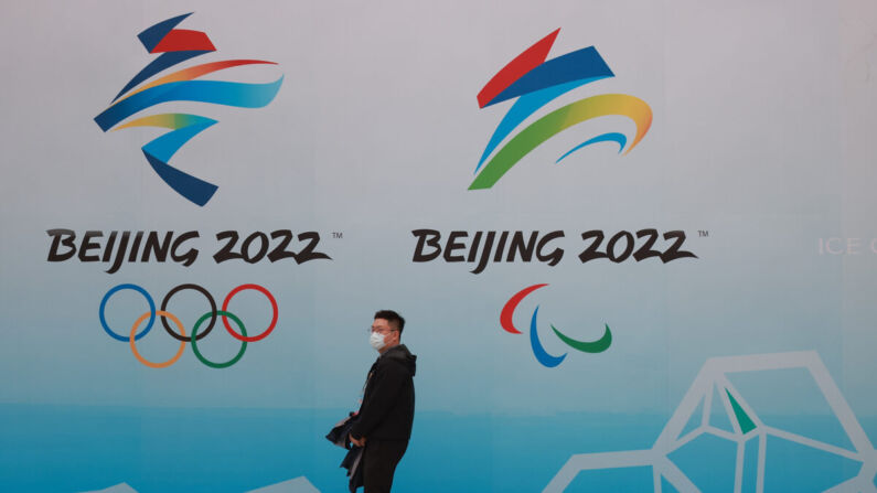Un hombre chino lleva una mascarilla mientras camina delante de los logotipos de los Juegos Olímpicos de Invierno de 2022 en el Centro Acuático Nacional de Beijing (China) el 9 de abril de 2021. (Lintao Zhang/Getty Images)