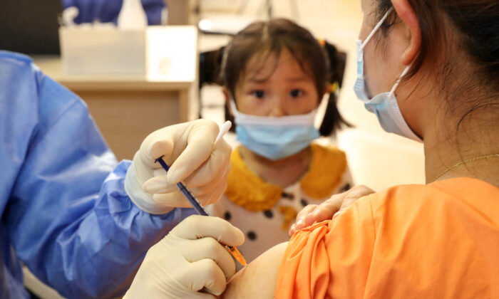 Una niña mira como una mujer recibe la vacuna contra el coronavirus COVID-19 del Grupo Nacional Biotec de China (CNBG) en Nantong, provincia de Jiangsu, China, el 5 de julio de 2021. (STR/AFP a través de Getty Images)