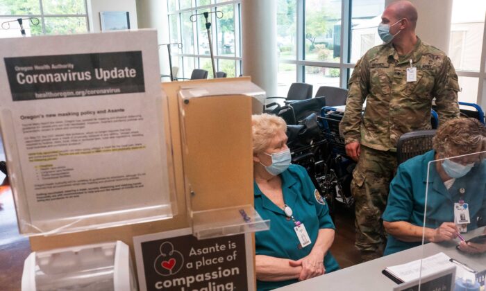 Un miembro de la Guardia Nacional de Oregón trabaja con el personal del hospital en una estación de admisión, en el Centro Médico Three Rivers Asante, en Grants Pass, Oregón, el 9 de septiembre de 2021. (Nathan Howard/Getty Images)