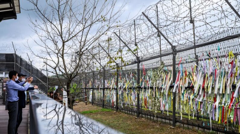 Los visitantes toman fotos de una valla adornada con cintas con mensajes escritos en ellas, en el "parque de la paz" ​​de Imjingak cerca de la Zona Desmilitarizada (DMZ) que separa Corea del Norte y Corea del Sur, en Paju el 21 de septiembre de 2021, mientras los surcoreanos celebran el anual Día de acción de gracias de Chuseok, que se extiende del 20 al 22 de septiembre (Anthony Wallace / AFP a través de Getty Images)