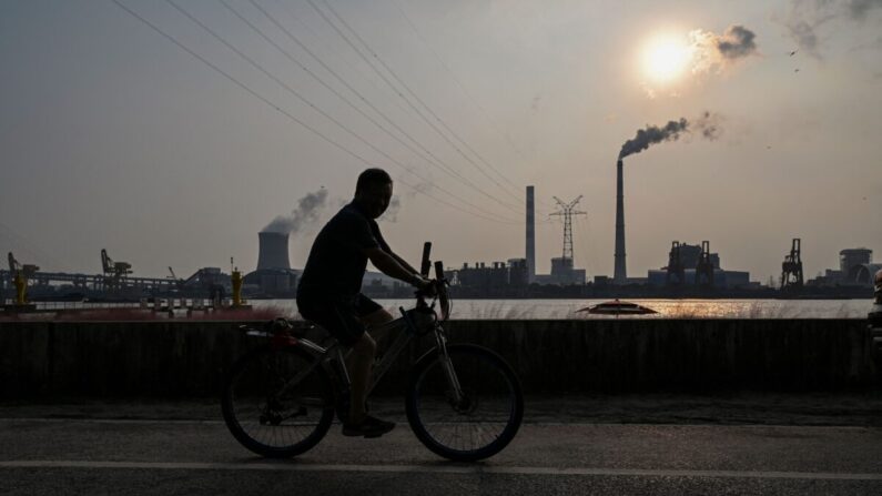 Un hombre monta en bicicleta en un paseo a lo largo del río Huangpu frente a la central eléctrica de carbón de Wujing en Shanghai el 28 de septiembre de 2021. (Hector Retamal/AFP vía Getty Images)