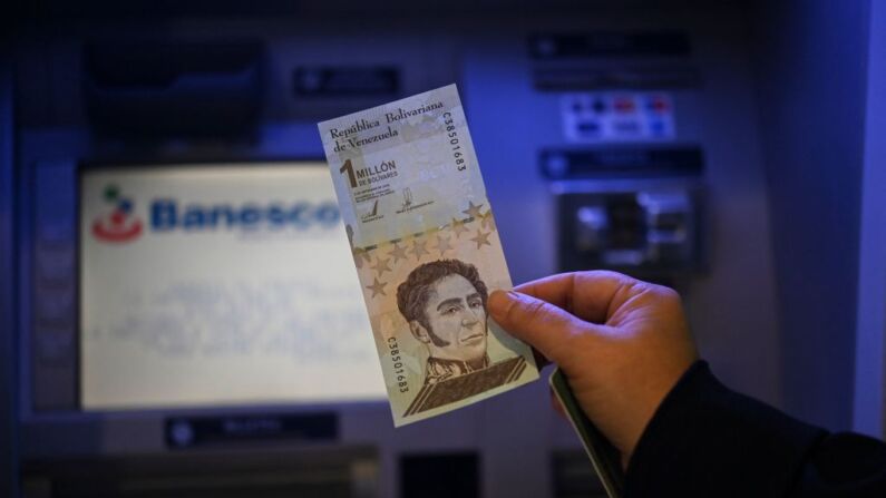 Una persona muestra un billete de un millón de bolívares que seguirá circulando, pero con un valor de un bolívar, ya que Venezuela presenta nuevos billetes para volver a recortar los ceros de su moneda, después de hacer un retiro de efectivo de un cajero automático en un banco en Caracas el 1 de octubre de 2021. El tipo de cambio oficial del bolívar venezolano pasó de 4.18 millones por dólar de la noche a la mañana a solo 4.18, ya que el empobrecido país recortó seis ceros de su moneda devastada por la inflación el viernes para simplificar las transacciones. (Foto de YURI CORTEZ/AFP a través de Getty Images)