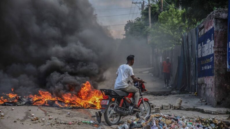 Un hombre conduce su bicicleta alrededor de unos neumáticos en llamas encendidos tras la convocatoria de una huelga general por parte de varias asociaciones profesionales y empresas para denunciar la inseguridad en Puerto Príncipe el 18 de octubre de 2021. (Richard Pierrin/AFP vía Getty Images)