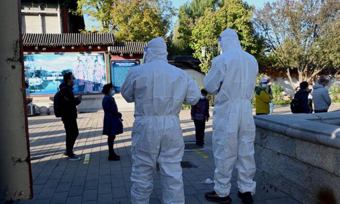 Trabajadores de la salud observan a las personas que hacen fila para las pruebas de COVID-19 en una estación de recolección de ácido nucleico, en Beijing, el 26 de octubre de 2021. (Noel Celis/AFP a través de Getty Images)