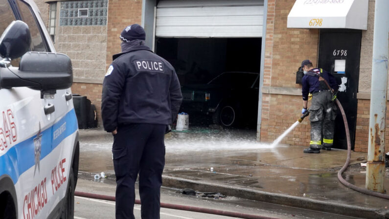 Un bombero de Chicago limpia con una manguera la sangre de la acera después de un tiroteo en un garaje de una empresa el 14 de marzo de 2021 en Chicago, Illinois.(Scott Olson/Getty Images)