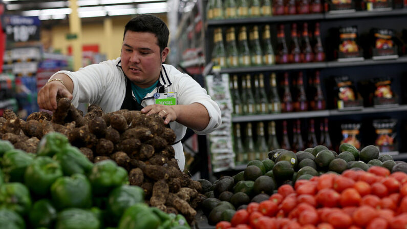 Dayngel Fernandez, empleado de Walmart, trabaja en el departamento de frutas y verduras almacenando estantes en una tienda Walmart en Miami, Florida, el 19 de febrero de 2015. Walmart anunció que aumentaría el salario mínimo para sus trabajadores a USD 11 trase la aprobación del proyecto de reforma fiscal. (Joe Raedle/Getty Images)