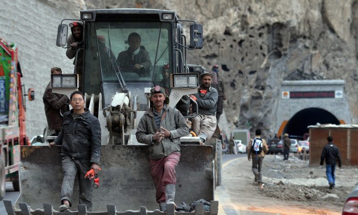 Una imagen de archivo de trabajadores paquistaníes y chinos sentados en una excavadora mientras salen de un túnel construido en el valle de Gojal, en el norte de Pakistán, el 25 de septiembre de 2015. El proyecto es parte de la Iniciativa de la Franja y la Ruta de China. (Aamir Qureshi/AFP/Getty Images)