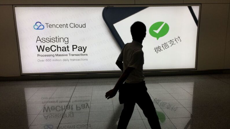 Un hombre camina en el aeropuerto internacional de Hong Kong el 21 de agosto de 2017, junto a un anuncio de la plataforma de redes sociales WeChat, propiedad de la empresa china Tencent. (Richard A. Brooks/AFP vía Getty Images)