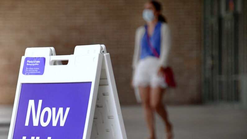 Peatones caminan junto a un cartel de " Ahora contratando" fuera de una tienda en Arlington, Virginia, el 16 de agosto de 2021. (Olivier Douliery/AFP vía Getty Images)
