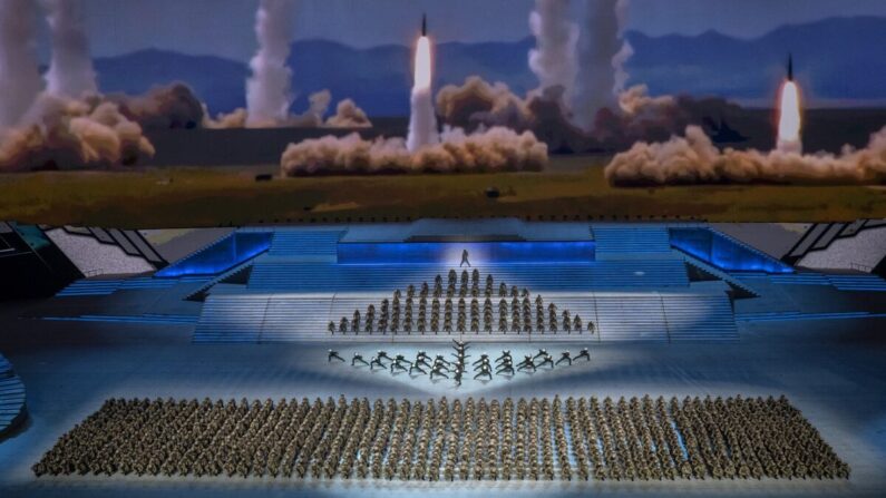 Artistas vestidos de militares bailan frente a una pantalla que muestra el lanzamiento de cohetes durante una gala masiva que marca el centenario del Partido Comunista en el estadio olímpico Nido de Pájaro en Beijing el 28 de junio de 2021. (Kevin Frayer/Getty Images)