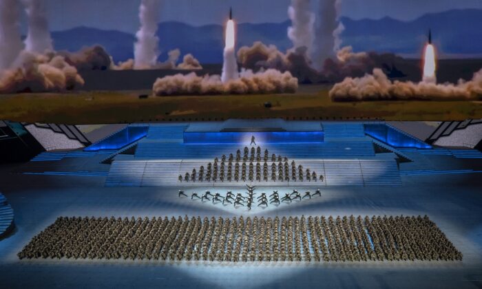 Artistas vestidos como militares bailan frente a una pantalla que muestra el lanzamiento de cohetes durante una gala masiva que marca el centenario del Partido Comunista, en el estadio olímpico Nido de Pajaro, en Beijing, China, el 28 de junio de 2021. (Kevin Frayer/Getty Images)