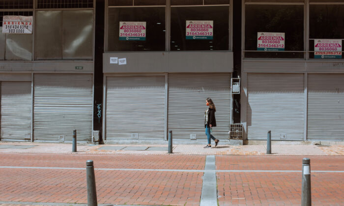 Un peatón camina junto a escaparates de negocios vacíos con carteles de alquiler en Bogotá, Colombia, el 15 de octubre de 2021. (Alejandro Gómez/The Epoch Times)