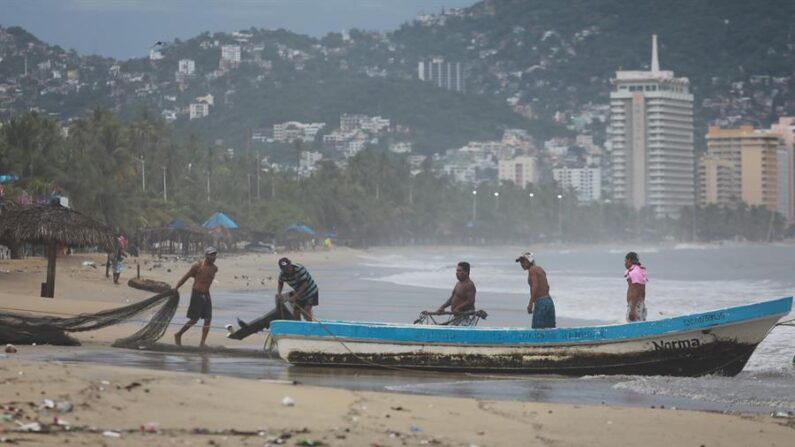 Un grupo de pescadores pone a salvo su embarcación, el 25 de octubre de 2021, en el balneario de Acapulco, estado de Guerrero (México). EFE/ David Guzmán