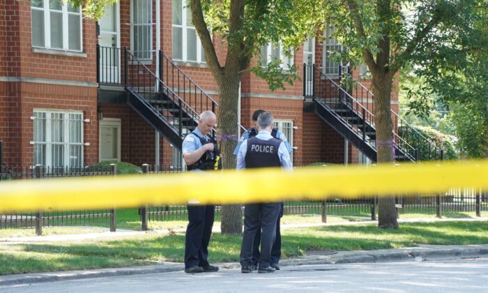 Dos policías hablan con un detective mientras investigan un tiroteo, en Chicago el 20 de agosto de 2021. (Cara Ding/The Epoch Times)
