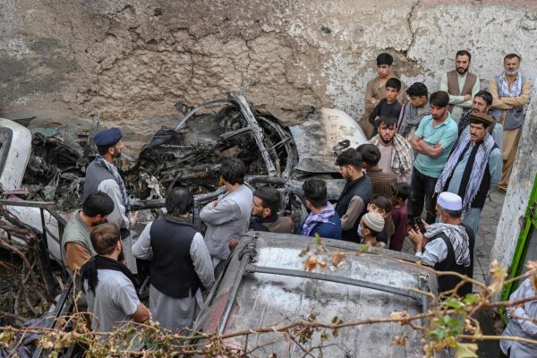 Los residentes afganos y los familiares de las víctimas se reúnen junto a un vehículo dañado dentro de una casa, un día después de un ataque aéreo con aviones no tripulados estadounidenses en Kabul, Afganistán, el 30 de agosto de 2021. (Wakil Kohsar/AFP a través de Getty Images)