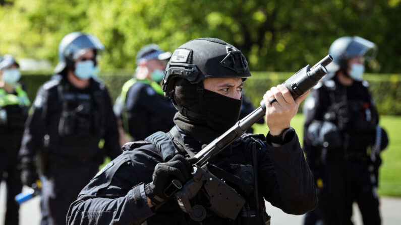 Un policía antidisturbios blande un arma mirando hacia adelante a los manifestantes cerca del Santuario del Recuerdo, en Melbourne, Australia, el 22 de septiembre de 2021. (Darrian Traynor/Getty Images)