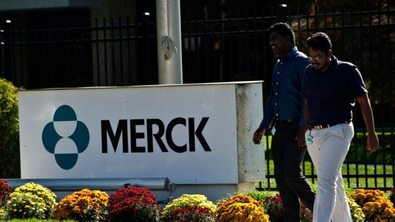 Unos empleados pasan por delante de un cartel de Merck frente al edificio de la compañía el 2 de octubre de 2013 en Summit, Nueva Jersey. (Kena Betancur/Getty Images)