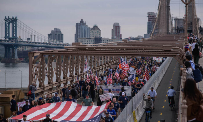 Trabajadores municipales marchan por el puente de Brooklyn durante una protesta contra el mandato de la vacuna COVID-19, en Nueva York, el 25 de octubre de 2021. (Ed Jones/AFP vía Getty Images)