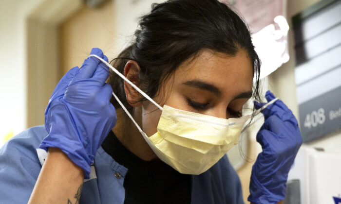 Una enfermera se quita cuidadosamente la mascarilla y el EPI después de atender a una paciente con COVID-19 en la unidad de cuidados intensivos del Centro Médico Harborview el 7 de mayo de 2020 en Seattle, Washington. (Karen Ducey/Getty Images)