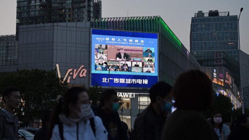 Un programa de noticias informa sobre la aparición del líder del PCCh, Xi Jinping, en una cumbre climática liderada por Estados Unidos, como se ve en una pantalla gigante en Beijing el 23 de abril de 2021. (Greg Baker/AFP a través de Getty Images)