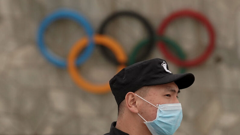 Un hombre lleva una mascarilla mientras pasa por delante del logotipo de los Juegos Olímpicos, en el parque olímpico de Beijing, el 25 de marzo de 2020, en Beijing, China. (Lintao Zhang/Getty Images)