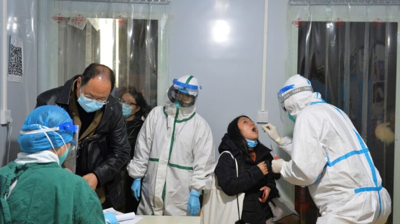 Esta foto tomada el 8 de diciembre de 2020 muestra a un trabajador sanitario realizando una prueba de ácido nucleico a un residente en Chengdu, en la provincia occidental china de Sichuan. (STR/AFP vía Getty Images)