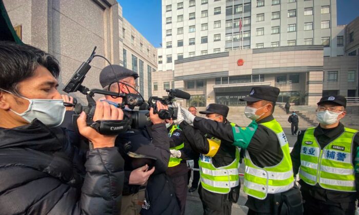 Un policía cubre una cámara para evitar que los periodistas graben imágenes fuera del Tribunal Popular del Nuevo Distrito de Pudong de Shanghai, en Shanghai, China, el 28 de diciembre de 2020. (LEO RAMIREZ/AFP a través de Getty Images)