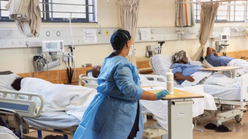 Un asistente de salud camina entre unos pacientes con COVID-19 en una sala del hospital de Khayelitsha, a unos 35 km del centro de Ciudad del Cabo, el 29 de diciembre de 2020. (Rodger Bosch/AFP vía Getty Images)