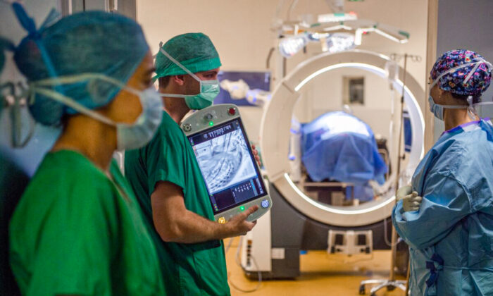 Un equipo de cirujanos utiliza un sistema de imágenes médicas en vivo Loop-X para asegurar el tratamiento de la columna vertebral de una paciente afectada por un cáncer de mama metastásico en el hospital afiliado a la Universidad (CHU) de Angers, al oeste de Francia, el 10 de junio de 2021. (AFP a través de Getty Images/Loic Venance)