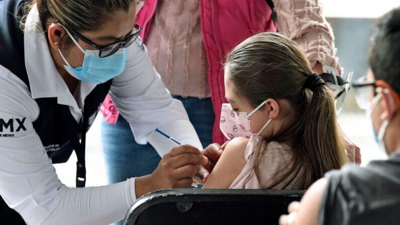 Una menor es inoculada con la primera dosis de la vacuna Pfizer-BioNtech contra la COVID-19 en la Biblioteca Vasconcelos de la Ciudad de México (México) el 25 de octubre de 2021. (Alfredo Estrella/AFP vía Getty Images)