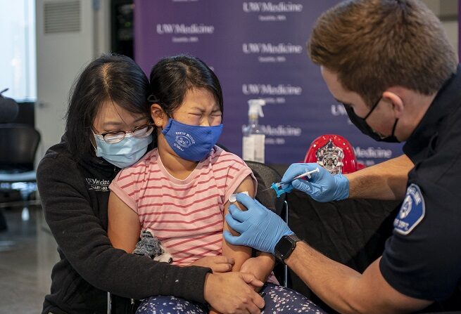 Elise Wong, de 7 años, se sienta en el regazo de su madre, Crystal Wong, mientras recibe la vacuna COVID-19 de Pfizer-BioNtech el 3 de noviembre de 2021 en Shoreline, Washington. (David Ryder/Getty Images)