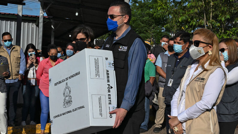 El presidente del Consejo Nacional Electoral (CNE), Kelvin Aguirre, se prepara para entregar simbólicamente una urna electoral al jefe de las Fuerzas Armadas de Honduras, Tito Livio Moreno, en Tegucigalpa (Honduras), el 23 de noviembre de 2021. (Orlando Sierra/AFP vía Getty Images)