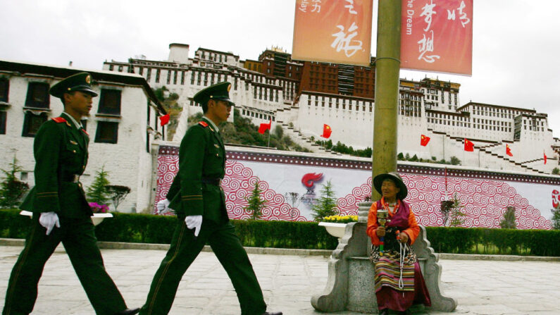 Un fiel tibetano mira a los policías chinos que patrullan el Palacio de Potala, en Lhasa, Tíbet, China, antes del relevo de la antorcha olímpica en Beijing, el 20 de junio de 2008. (Guang Niu/Getty Images)