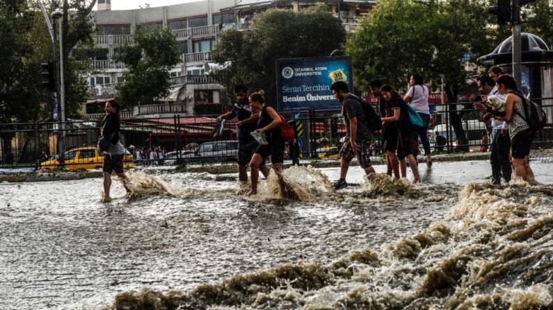 En una imagen de archivo, los peatones caminan a través de las aguas de la inundación después de un fuerte aguacero de lluvia y granizo en Besiktas, cerca de Estambul (Turquía), el 27 de julio de 2017. (Bulent Kilic/AFP vía Getty Images)