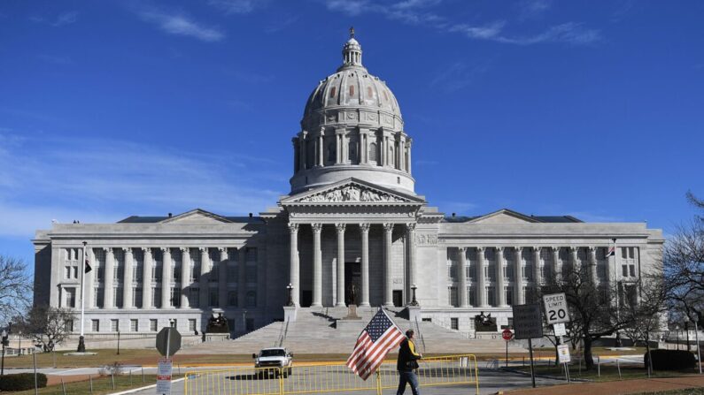 Un hombre agita una bandera estadounidense mientras camina fuera del edificio del Capitolio del Estado de Missouri en Jefferson City, Mo, el 20 de enero de 2021. (Michael B. Thomas/Getty Images)