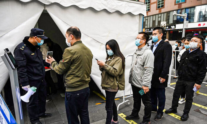 La gente hace fila para recibir una dosis de refuerzo de la vacuna contra el coronavirus, en una tienda de campaña instalada fuera de un centro comercial, en Beijing, el 1 de noviembre de 2021. (Greg Baker/AFP a través de Getty Images)