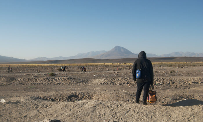 Un migrante mira a través de la frontera hacia Chile el 26 de octubre de 2021. (Cesar Calani Cosso/The Epoch Times)