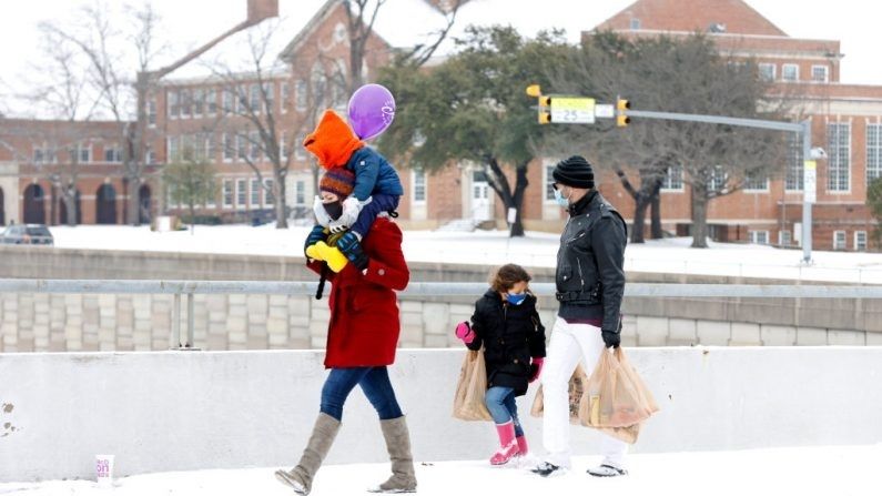FORT WORTH, TX - 17 DE FEBRERO: Una familia camina hacia su casa con los víveres después de una tormenta el 17 de febrero de 2021 en Fort Worth, Texas. (Ron Jenkins/Getty Images)
