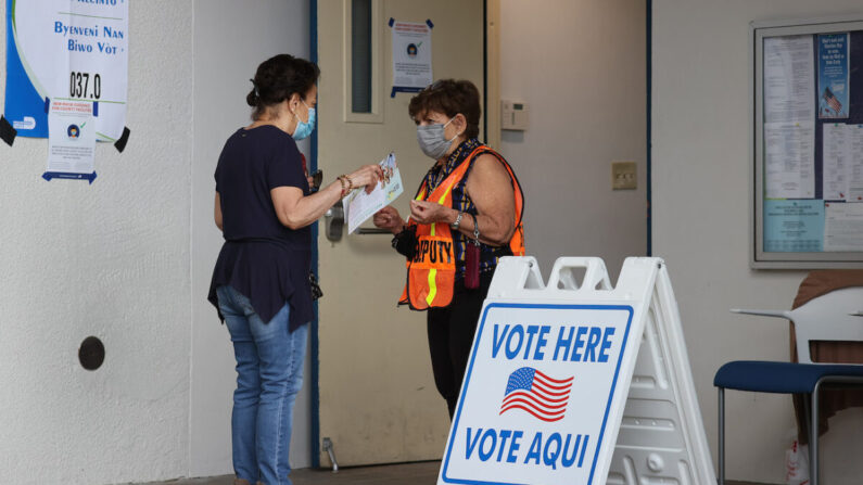 Un trabajador electoral habla con un votante a la entrada de un colegio electoral el día de las elecciones en Miami Beach, Florida, el 2 de noviembre de 2021. (Joe Raedle/Getty Images)