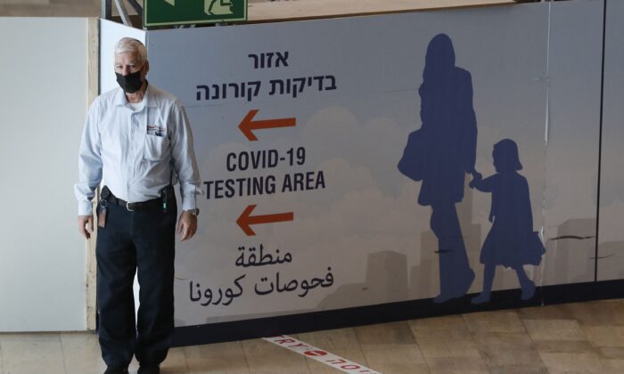 Un miembro del personal ayuda a los pasajeros que llegan al aeropuerto israelí Ben Gurion en Lod, al este de Tel Aviv, el 28 de noviembre de 2021. (Ahmad Gharabli/AFP vía Getty Images)