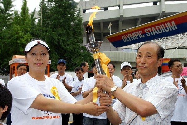 Huang Xiaomin (izquierda), embajadora asiática de la Antorcha de los Derechos Humanos, entrega la antorcha a Jeong Gujin (derecha), vicepresidente de la rama asiática de la CIPFG (Coalición para Investigar la Persecución de Falun Gong), en el Estadio Olímpico de Seúl, Corea del Sur, el 2 de julio de 2007. (Kim Kukhwan/Epoch Times)